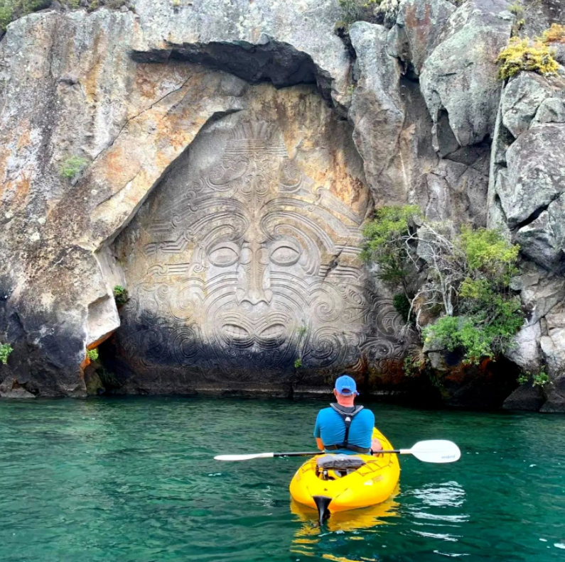 A kayaker looking a rock carvings